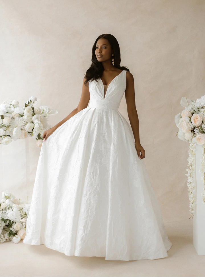front of abella parrish e565 ivory jacquard a-line wedding dress with a V neckline and floral print