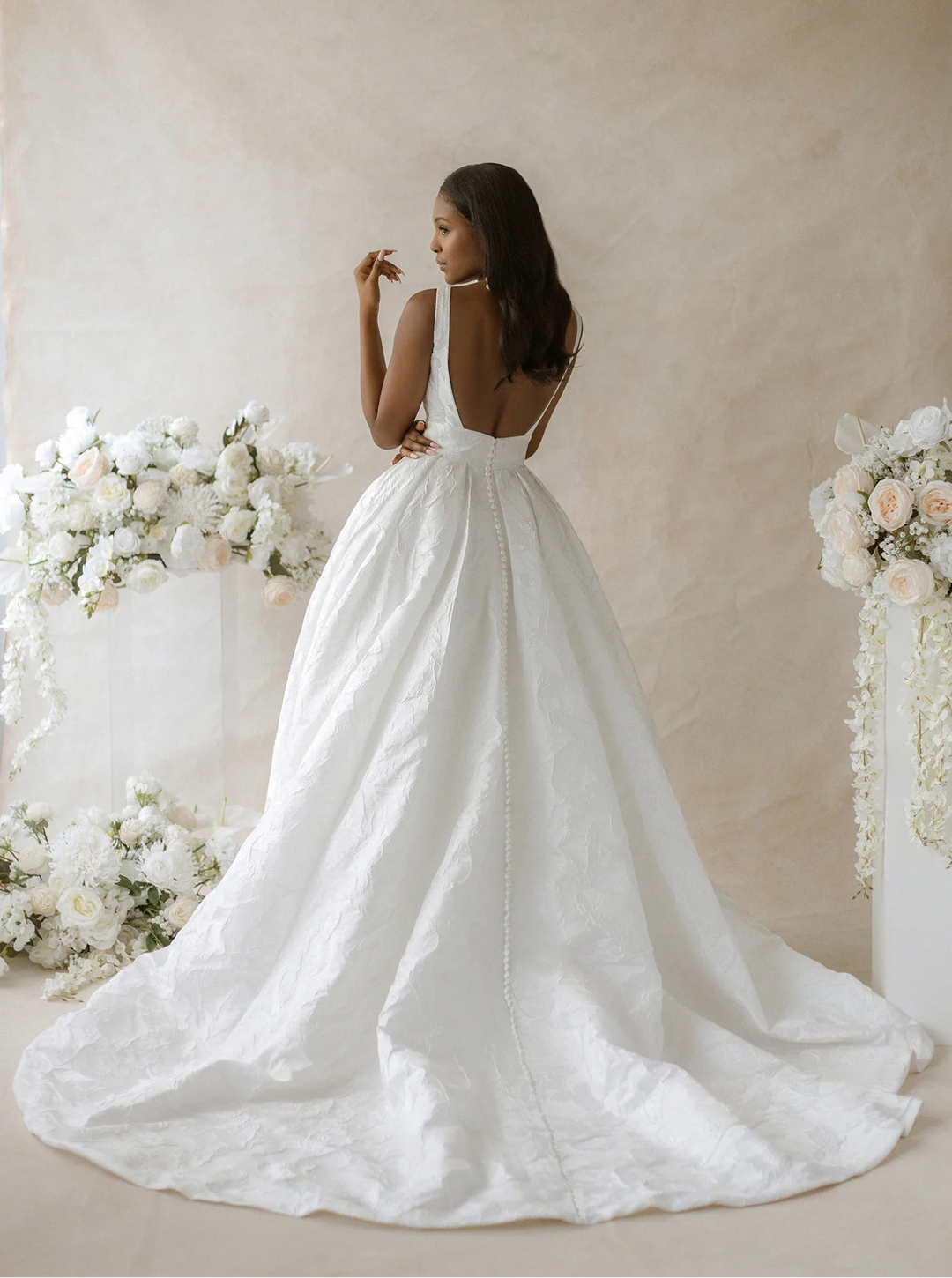 back of abella parrish e565 ivory jacquard a-line wedding dress with an open square back and chapel length train with buttons down the back