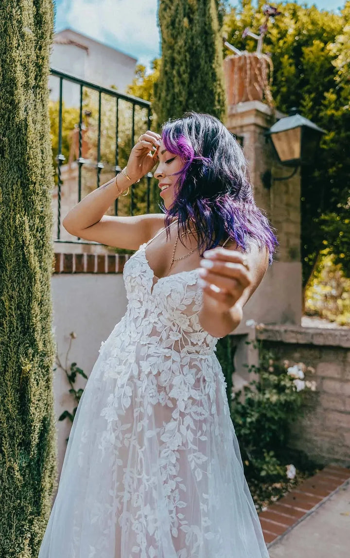 close up of the front of all who wander haven champagne tulle a-line wedding dress with a v neckline and sheer floral skirt