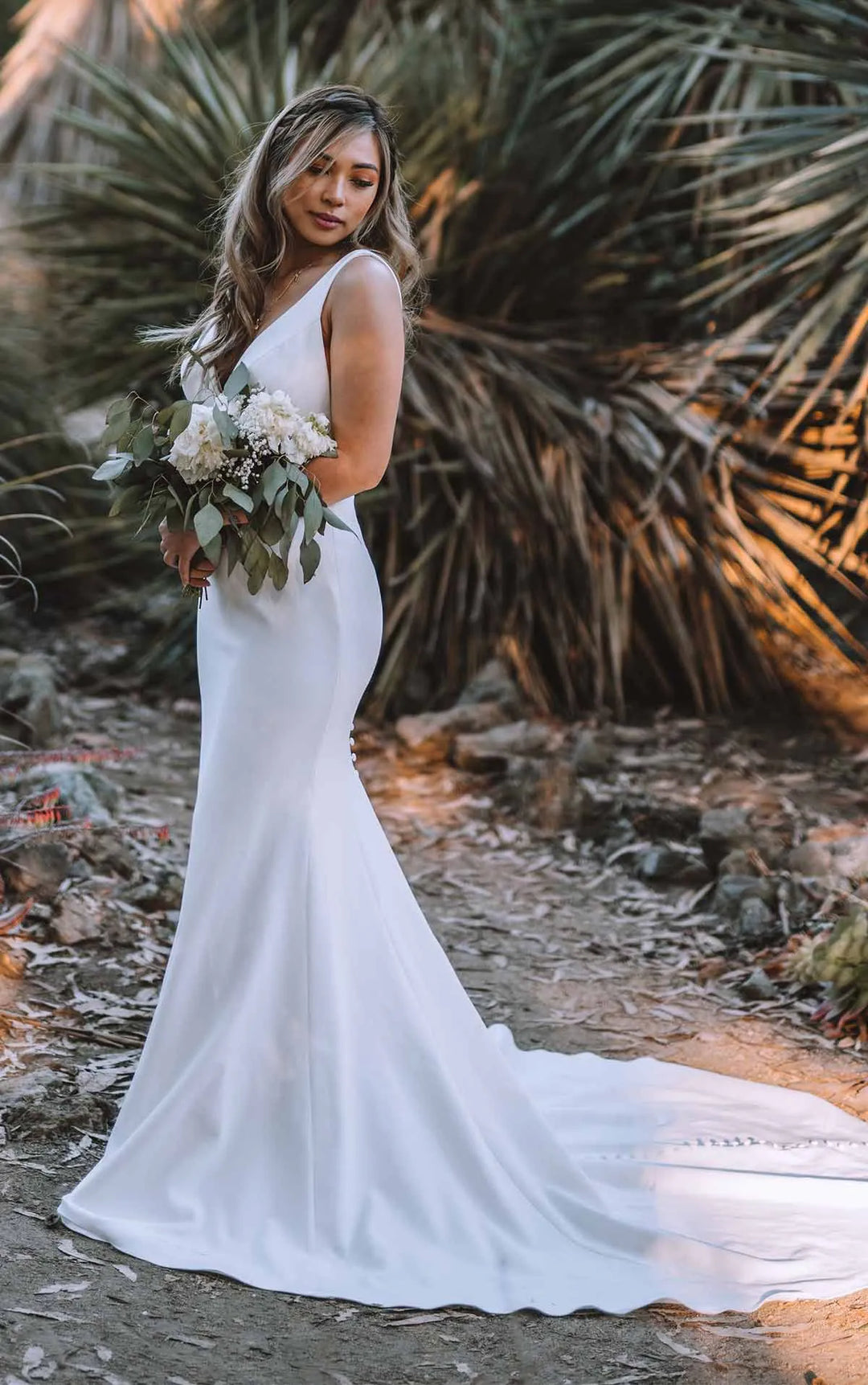 all who wander iona crepe fit and flare wedding dress showing side of gown, highlighting the chapel length train with buttons down the back