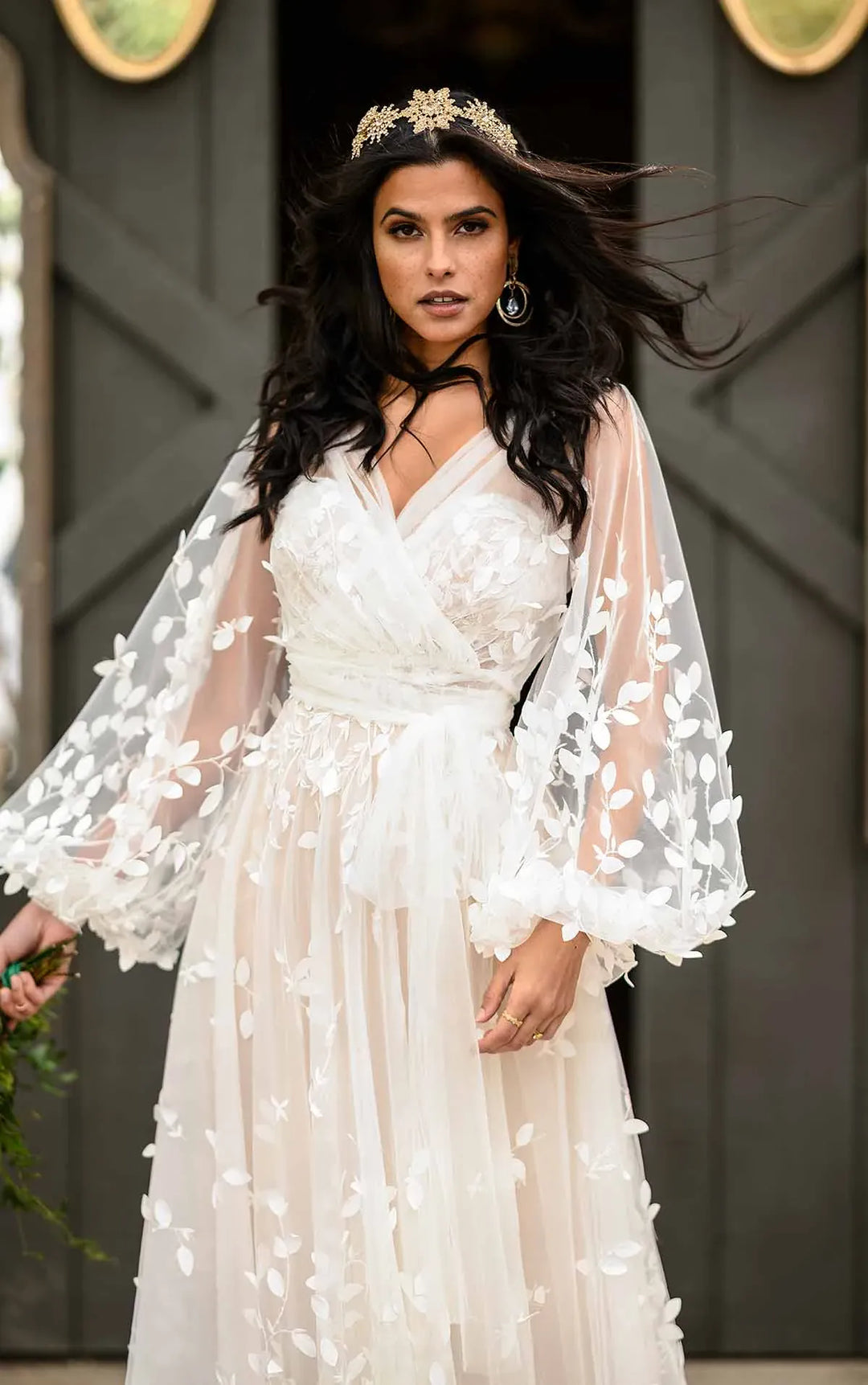 Woman in a white floral dress with sheer sleeves against a dark background