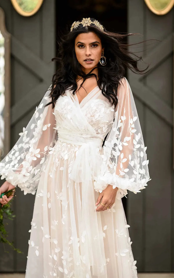 Woman in a white floral dress with sheer sleeves against a dark background