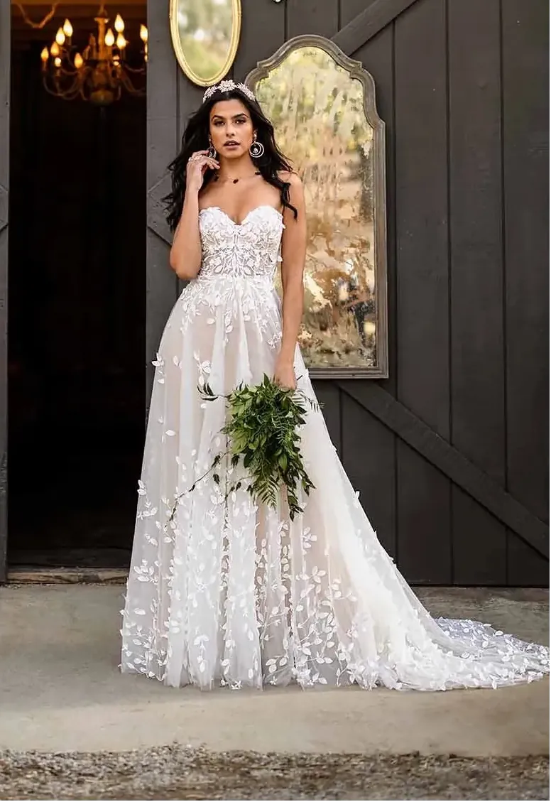 Woman in a white wedding dress holding a bouquet in front of a dark wooden door.