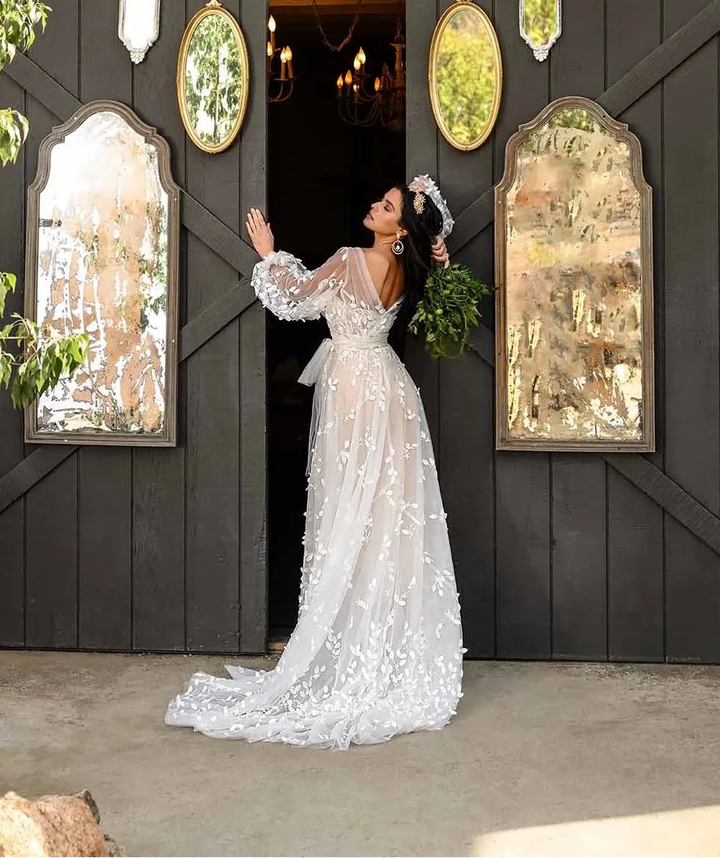 Woman in a white wedding dress standing in front of a dark wooden barn door with mirrors and antlers.