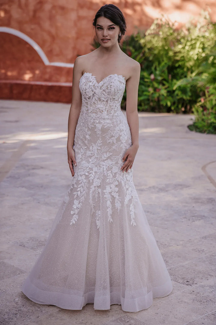 Woman wearing a strapless lace wedding dress outdoors.