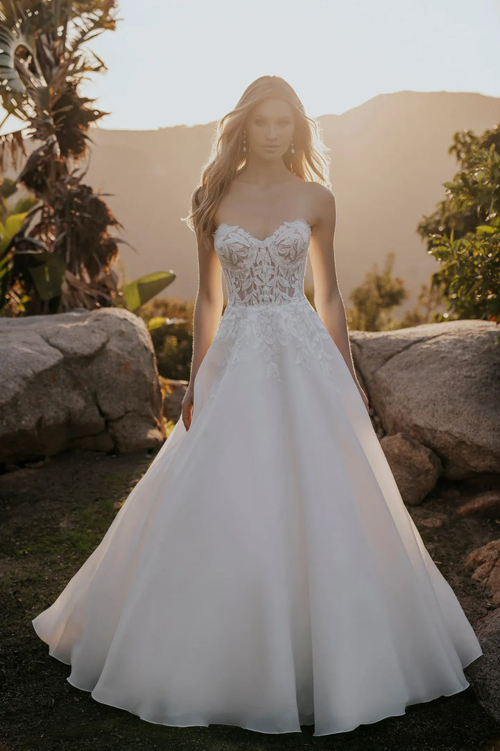 Woman wearing a white wedding dress with lace detailing in a natural setting.