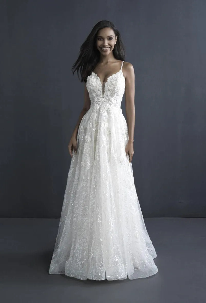 A woman modeling a white lace A-line wedding gown with spaghetti straps, a sweetheart neckline, and a full floor-length skirt against a dark gray studio backdrop.