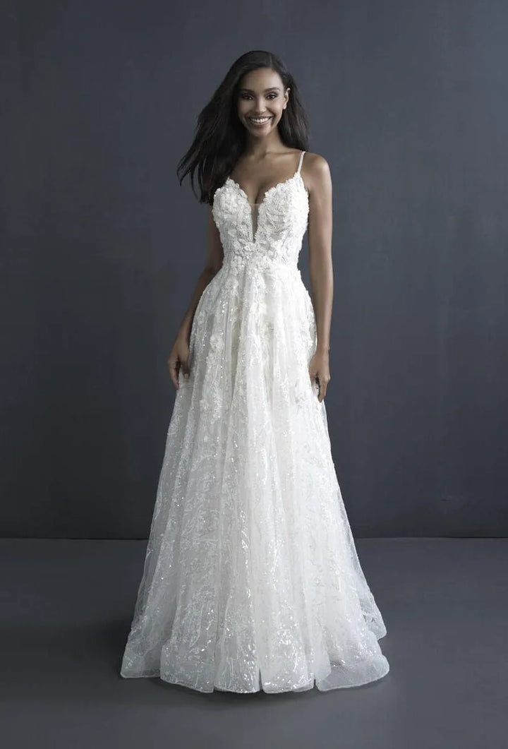 A woman modeling a white lace A-line wedding gown with spaghetti straps, a sweetheart neckline, and a full floor-length skirt against a dark gray studio backdrop.