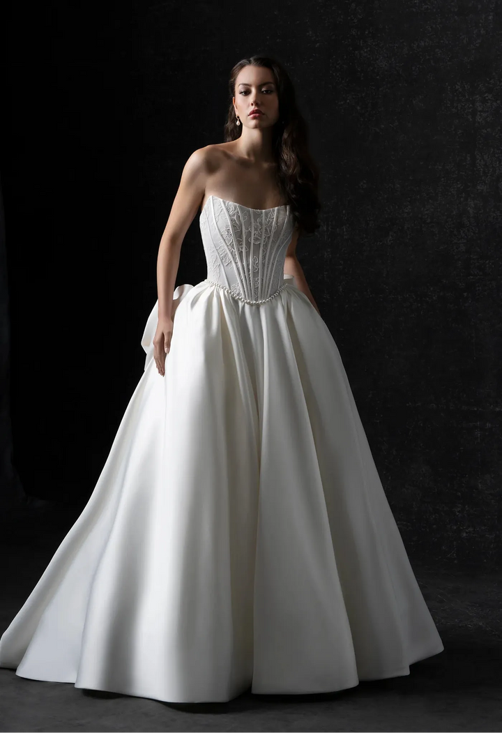 Woman wearing a white strapless gown against a dark background