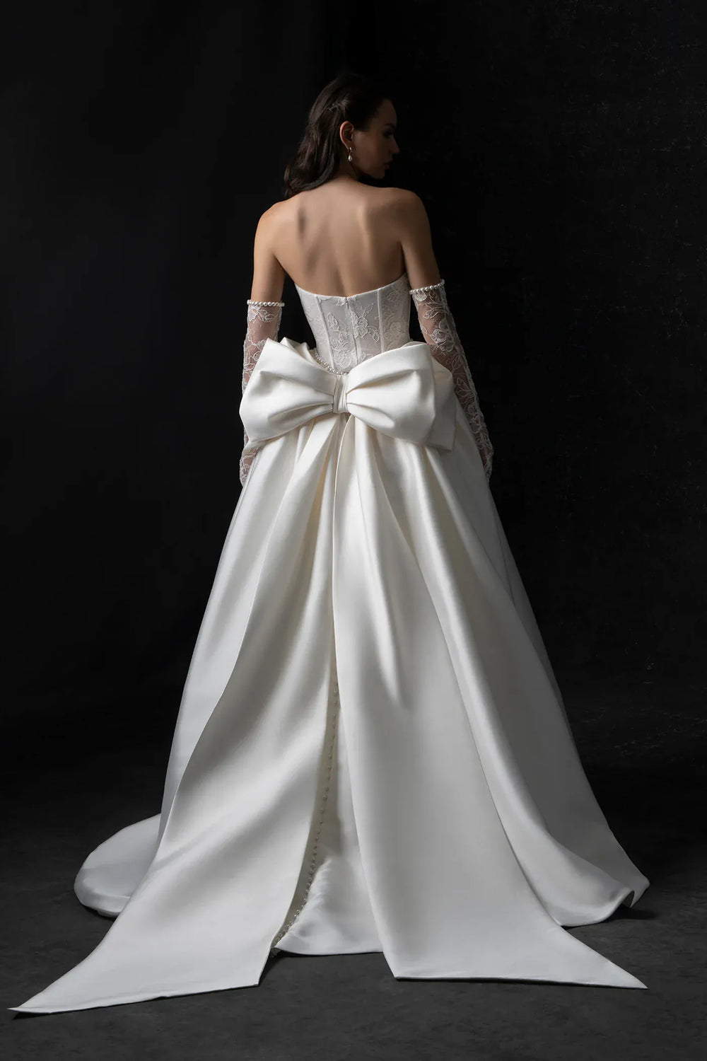 White wedding dress with a large bow on a black background