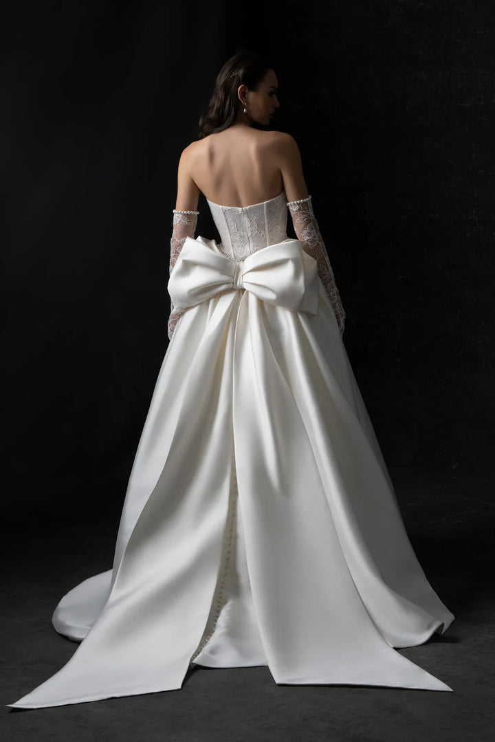 White wedding dress with a large bow on a black background