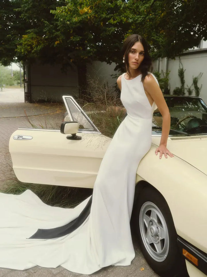 full front of alyne lillian ivory crepe sheath wedding dress with a modest neckline and black bow accent