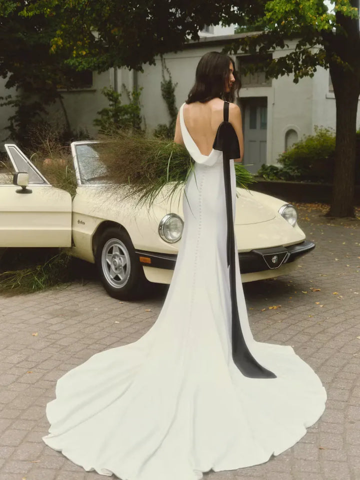 full back of alyne lillian ivory crepe sheath wedding dress with a cowl back and black bow accent