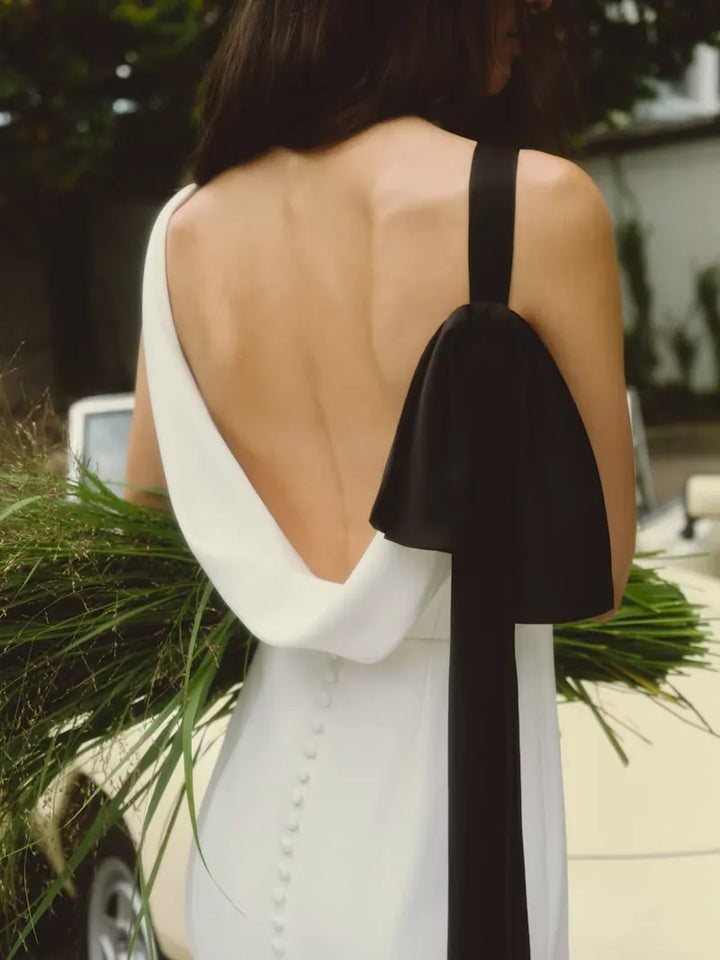 close up of alyne lillian ivory crepe sheath wedding dress showing the black bow at the back