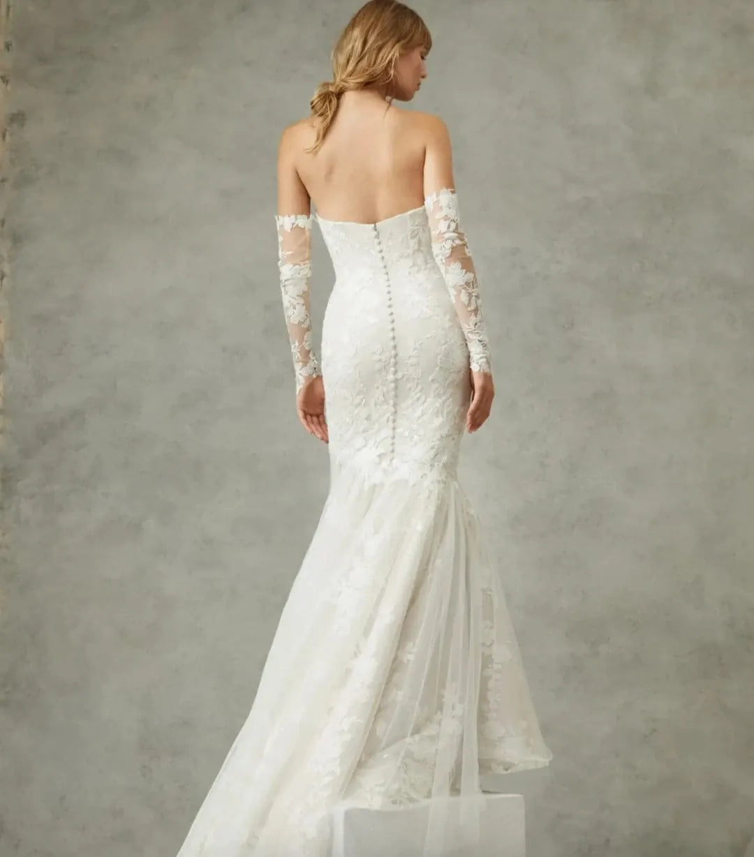 White lace wedding dress with long sleeves on a neutral background