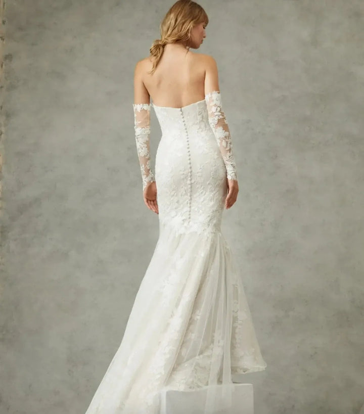 White lace wedding dress with long sleeves on a neutral background