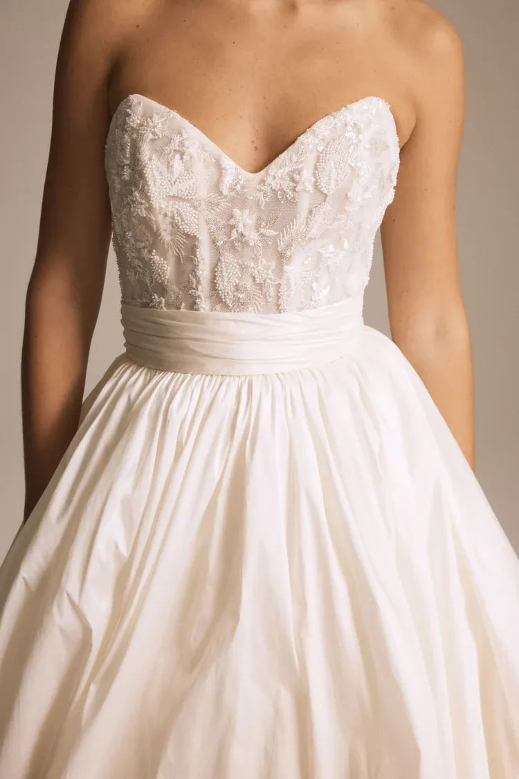 close up of amsale pepper ivory taffeta ball gown wedding dress with a beaded bodice and pockets in the skirt