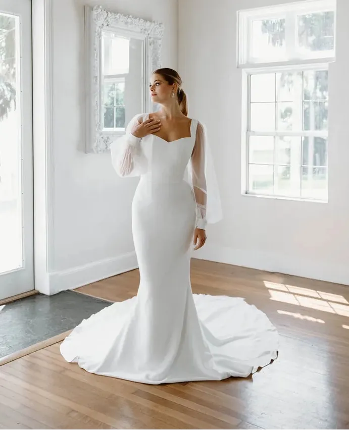 full front of angel rivera viola ivory crepe fitted wedding dress with long flowy sleeves