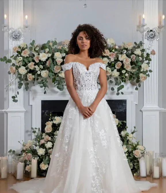 front of flores by angel rivera wish ivory tulle a-line wedding dress with floral appliques throughout and off the shoulder straps