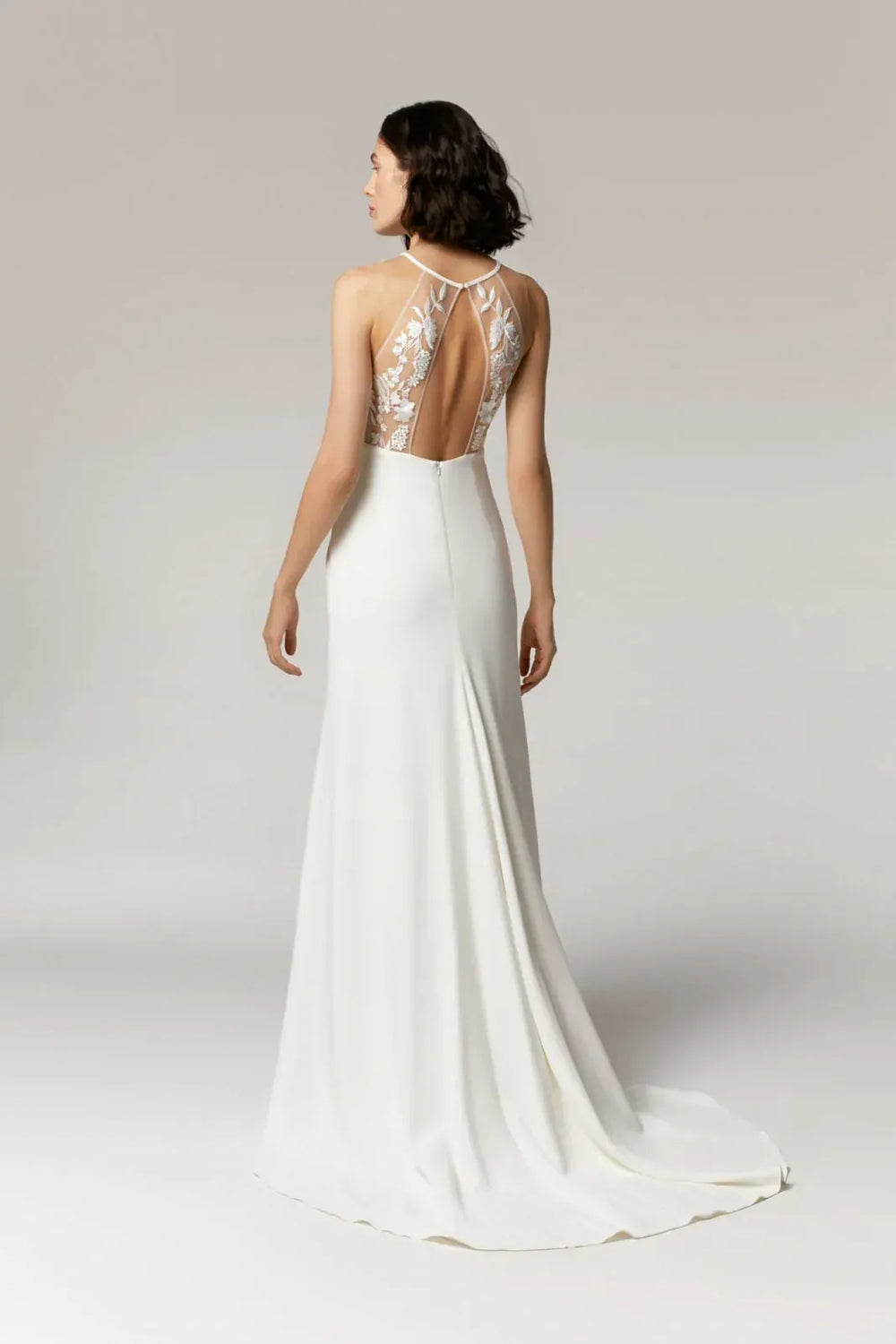 White wedding dress with lace back on a plain background