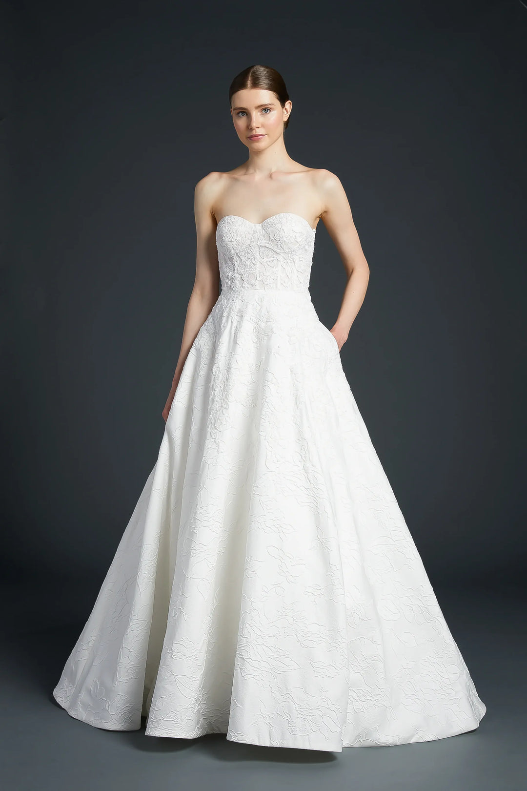 White strapless wedding dress on a model against a dark background