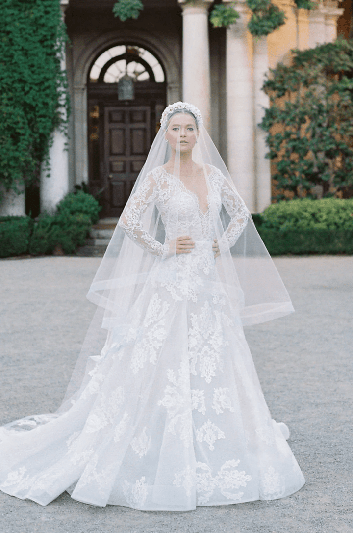 Woman in a white wedding dress with a long veil standing in front of a classical building.