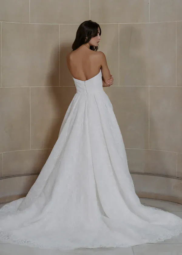 full back of anne barge graham ivory lace a-line wedding dress with a strapless neckline and chapel length train