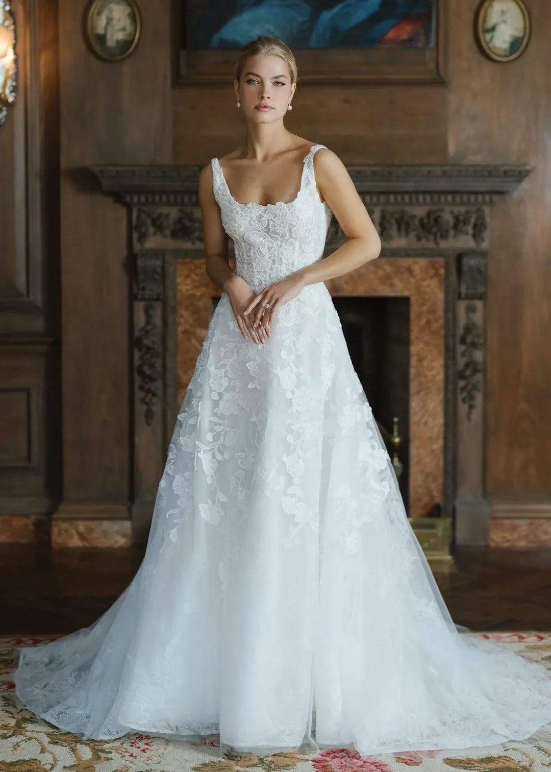 Woman in a white wedding dress standing in an elegant room with wooden walls and a fireplace.