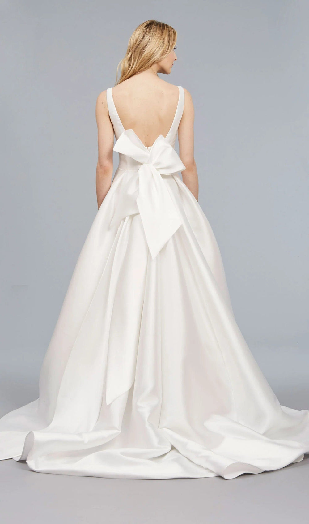 White wedding dress with a large bow at the back on a plain background