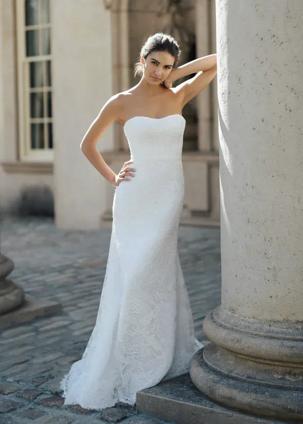 Woman in a white wedding dress standing next to stone columns.