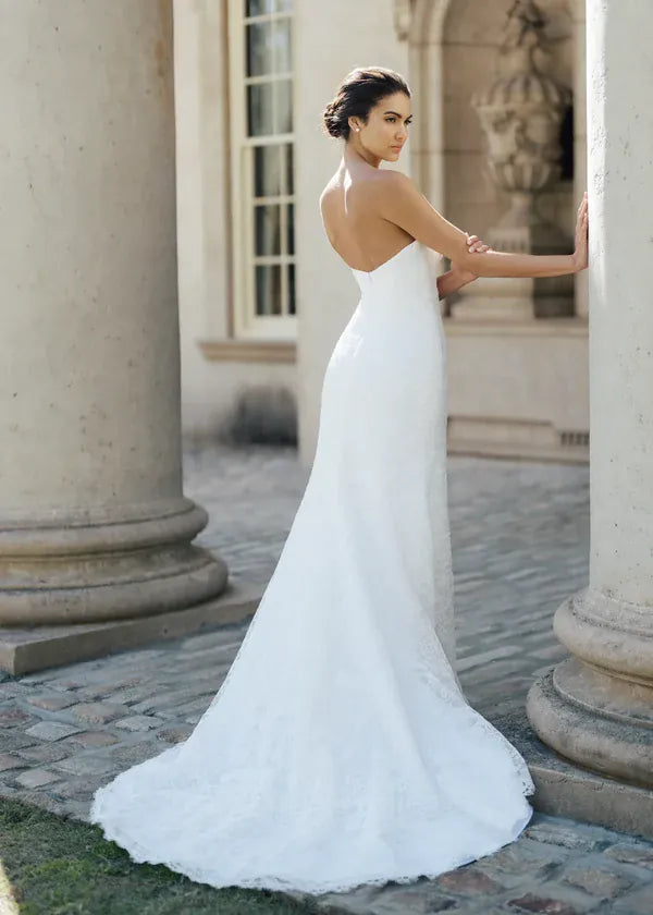Woman in a white wedding dress standing between two stone columns.