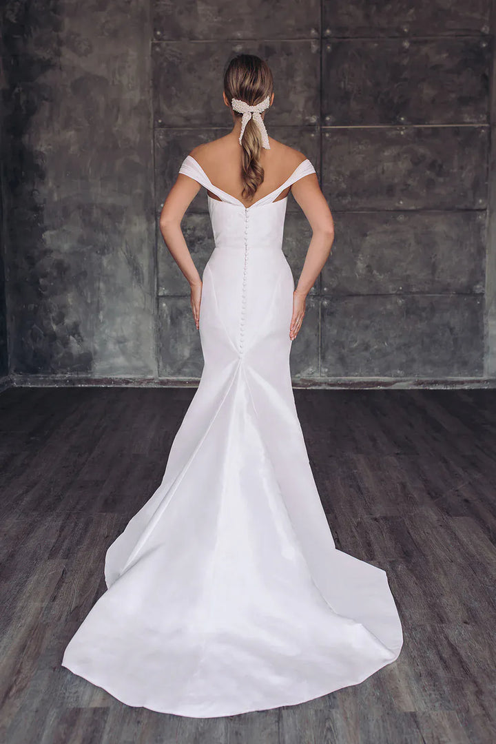 Woman wearing a white wedding dress with a plain background