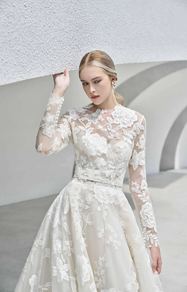 Woman wearing a white lace wedding dress against a modern architectural background
