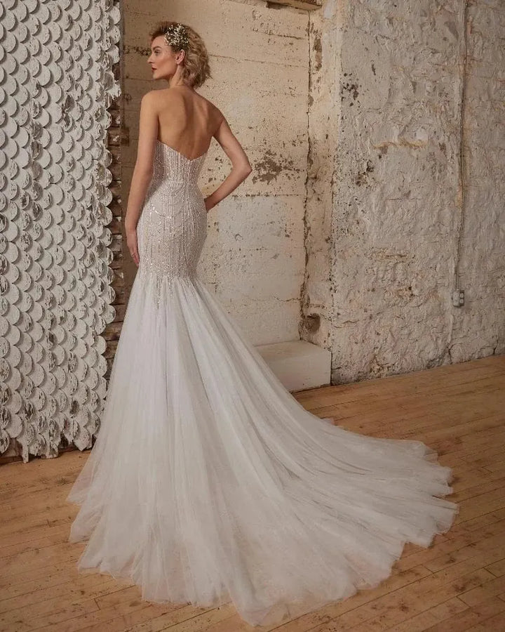 back of calla blanche wednesday champagne tulle fit and flare wedding dress with beaded bodice and flared tulle skirt that ends in a chapel length train