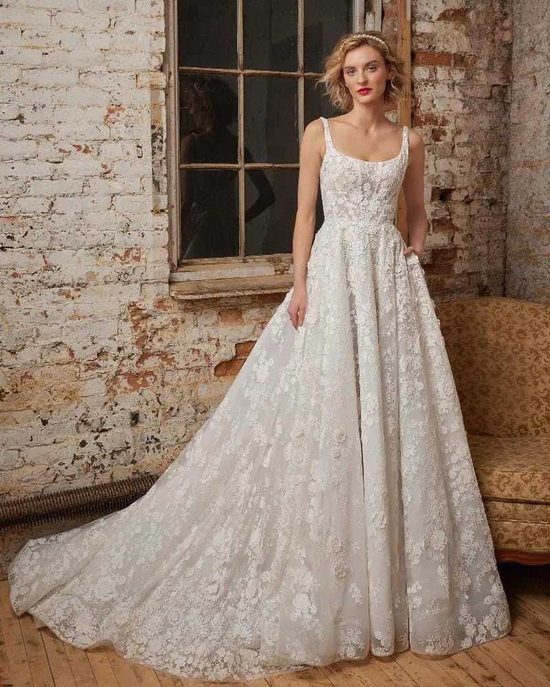 Woman wearing a lace wedding dress in an industrial-style room with brick walls.