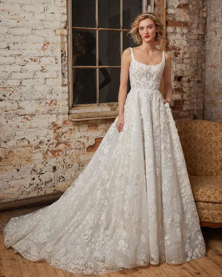 Woman wearing a lace wedding dress in an industrial-style room with brick walls.