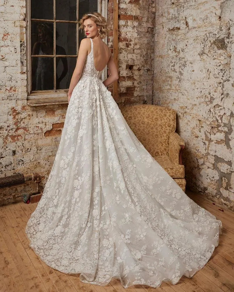 Woman in a lace wedding dress standing in an industrial-style room with brick walls.