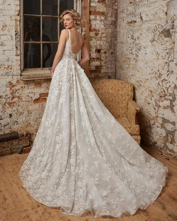 Woman in a lace wedding dress standing in an industrial-style room with brick walls.