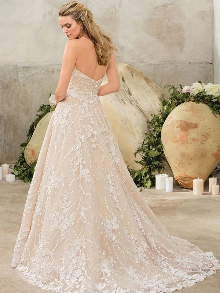 Woman in a lace wedding dress standing in front of decorative stones and flowers.