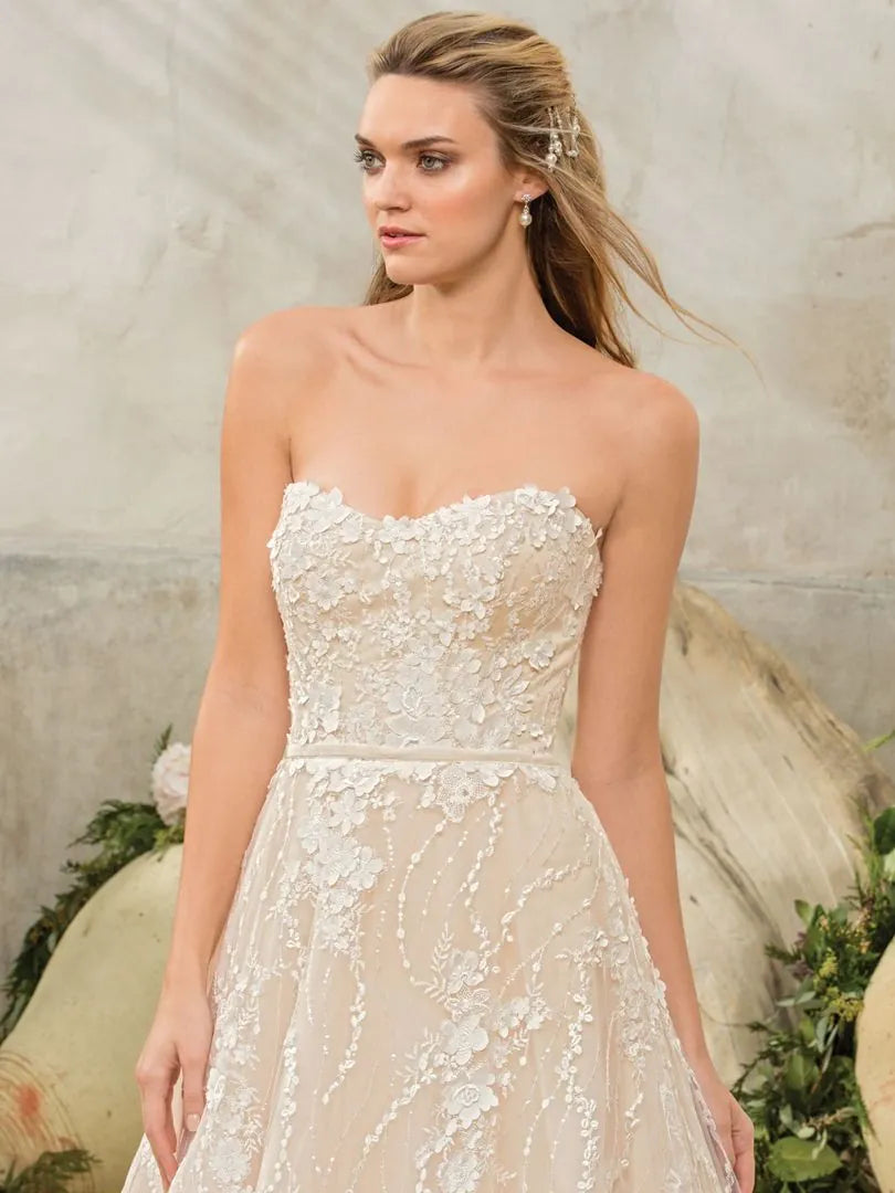 Woman wearing a strapless lace wedding dress against a neutral background
