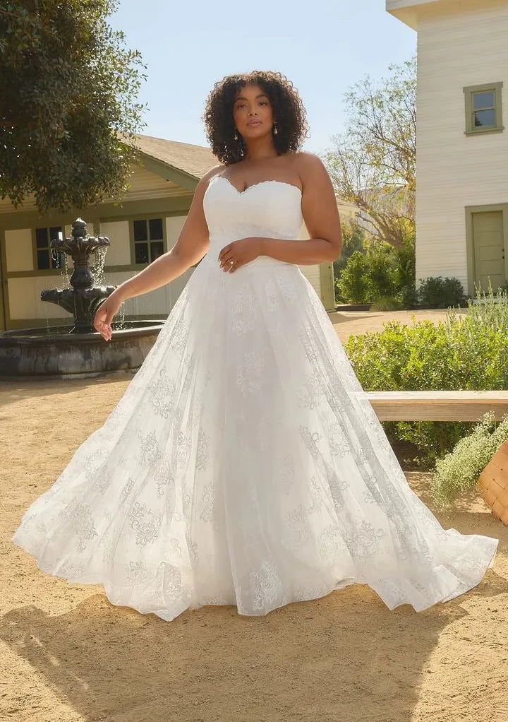 Woman in a white wedding dress standing outdoors with a fountain and building in the background