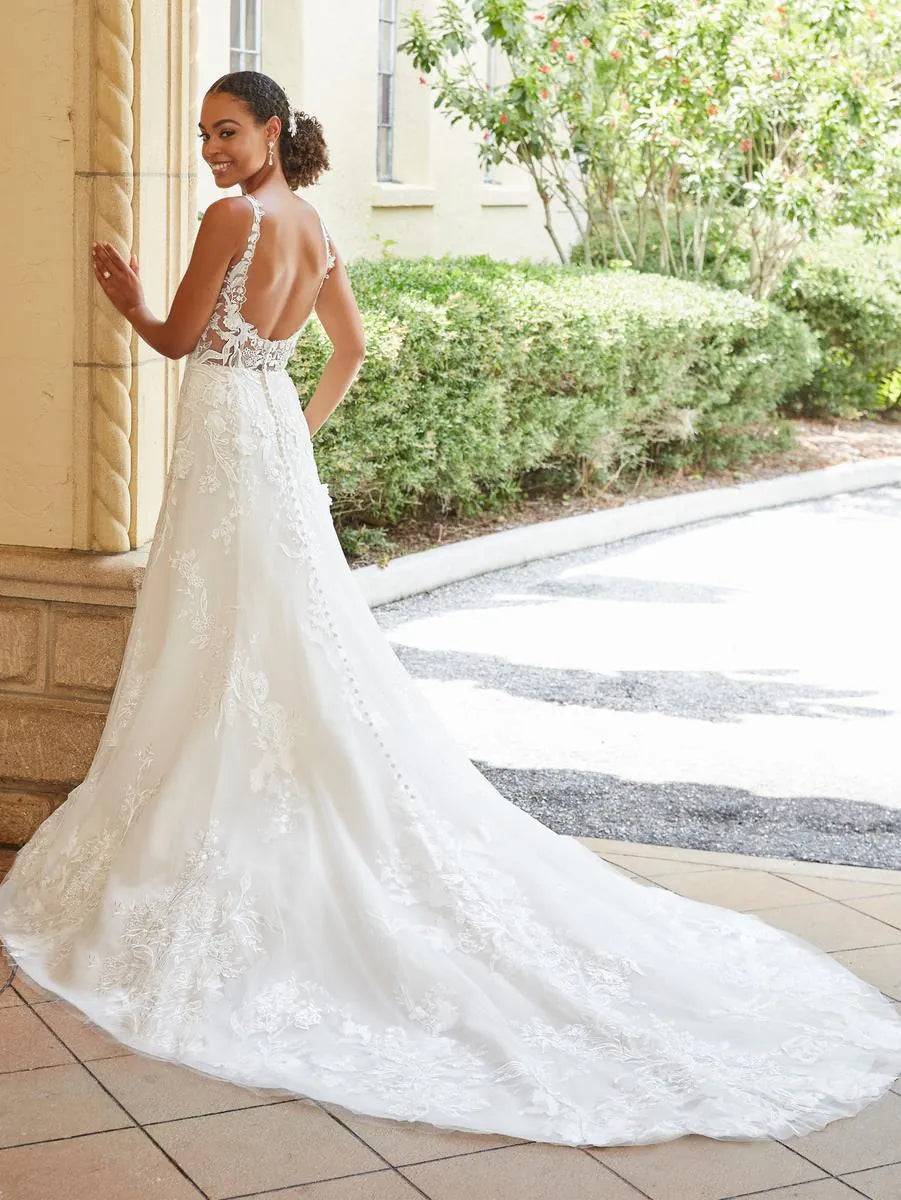 Woman in a white lace wedding dress standing outdoors.
