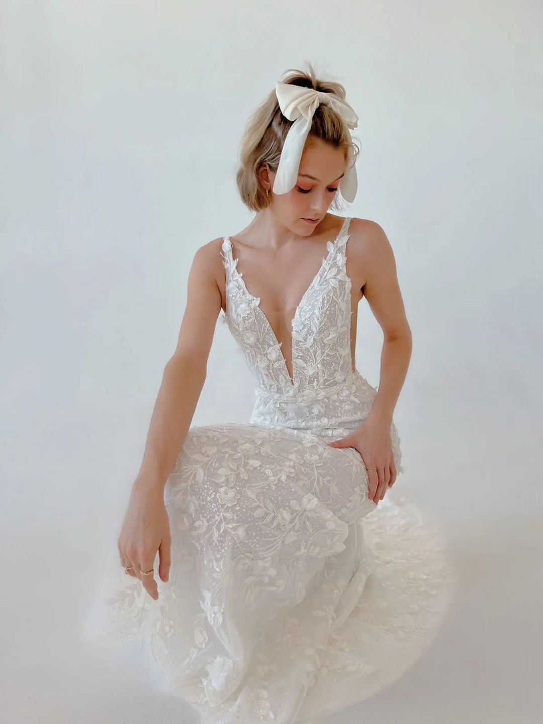 Woman wearing a white lace wedding dress with a plain background