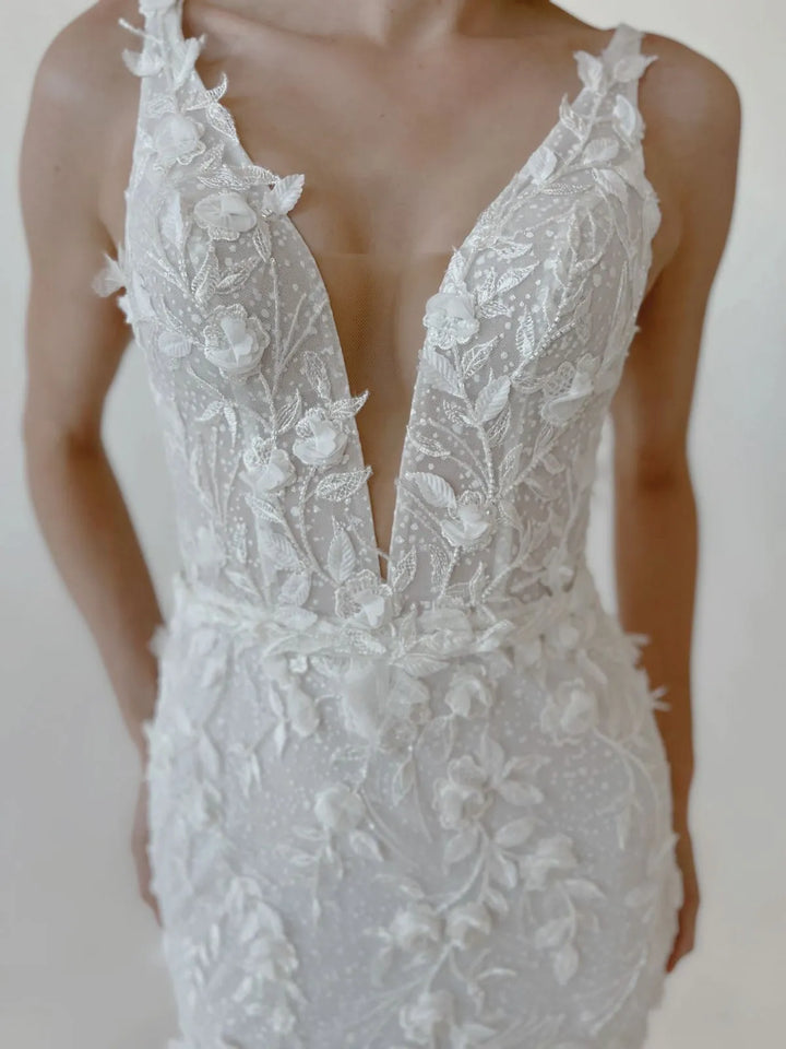 White lace wedding dress with a deep neckline on a white background