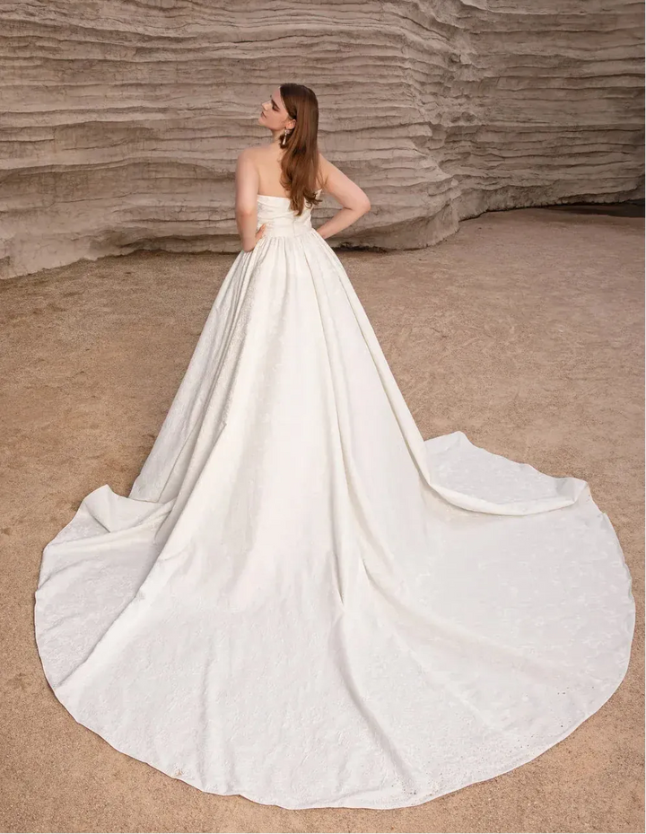 Woman in a white wedding dress standing in a desert landscape with rock formations.