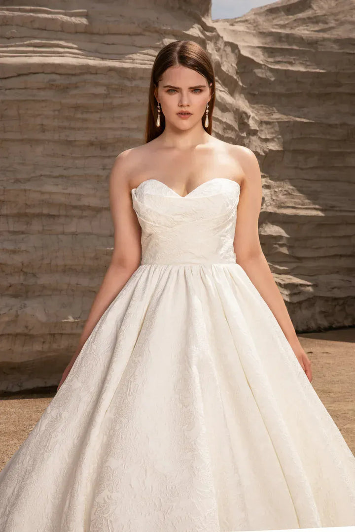 Woman wearing a strapless wedding dress against a stone wall background