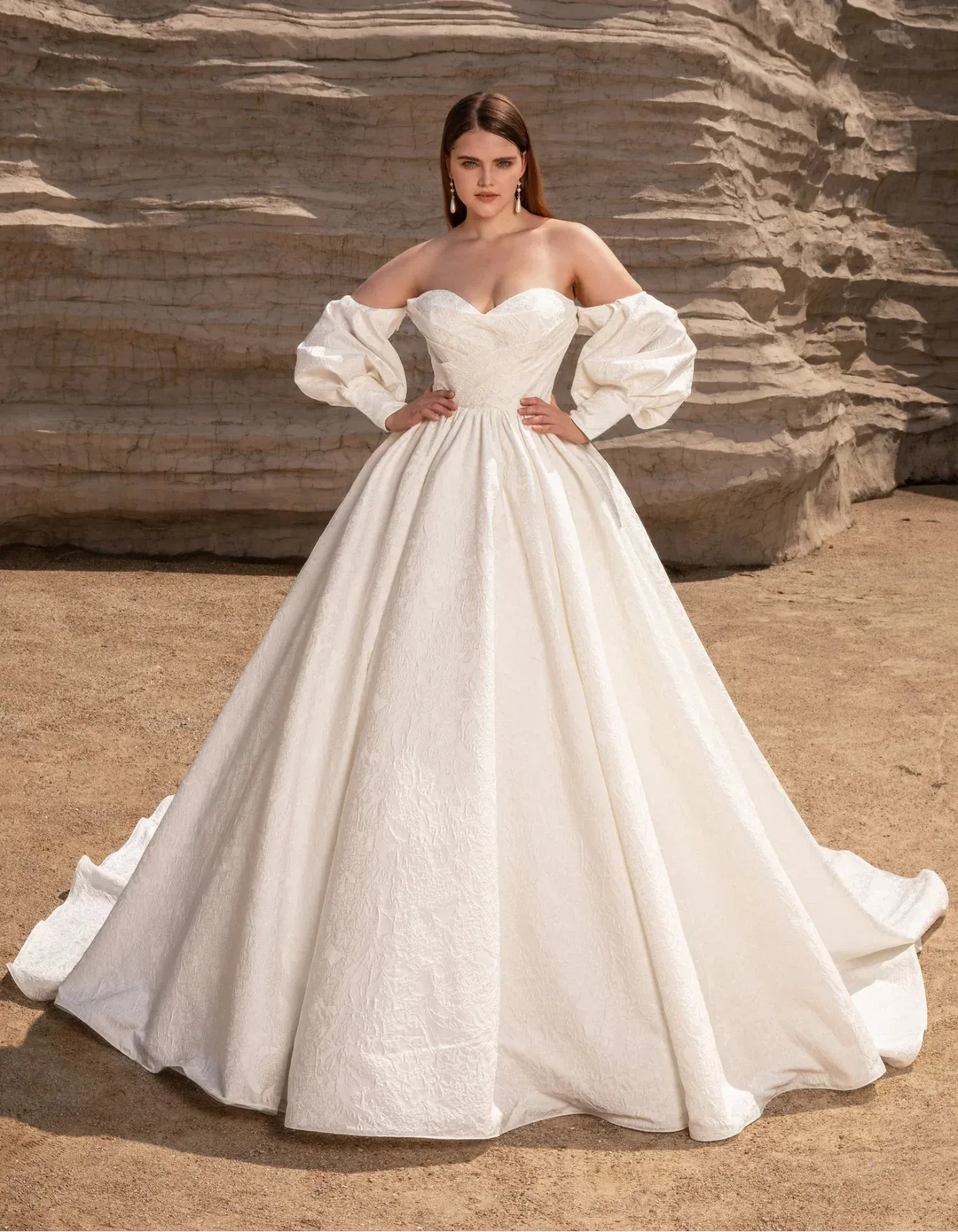 Woman in a white wedding dress standing against a rocky background