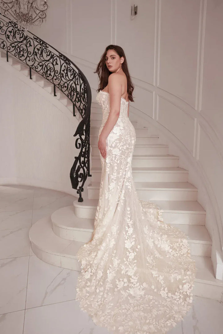 Woman in a white sequin gown standing on a staircase with decorative railings.