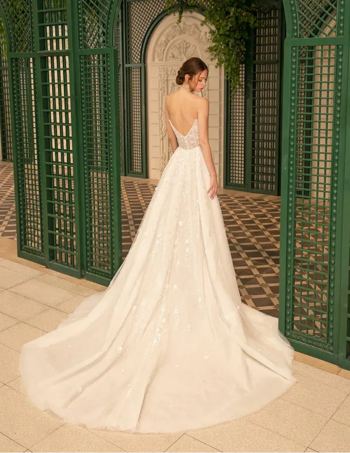 Woman in a white wedding dress standing in front of a decorative green archway.