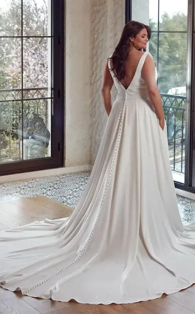full back of eddy k addison ivory crepe a-line wedding dress with a deep v neckline and beaded accents, and a chapel length train with buttons